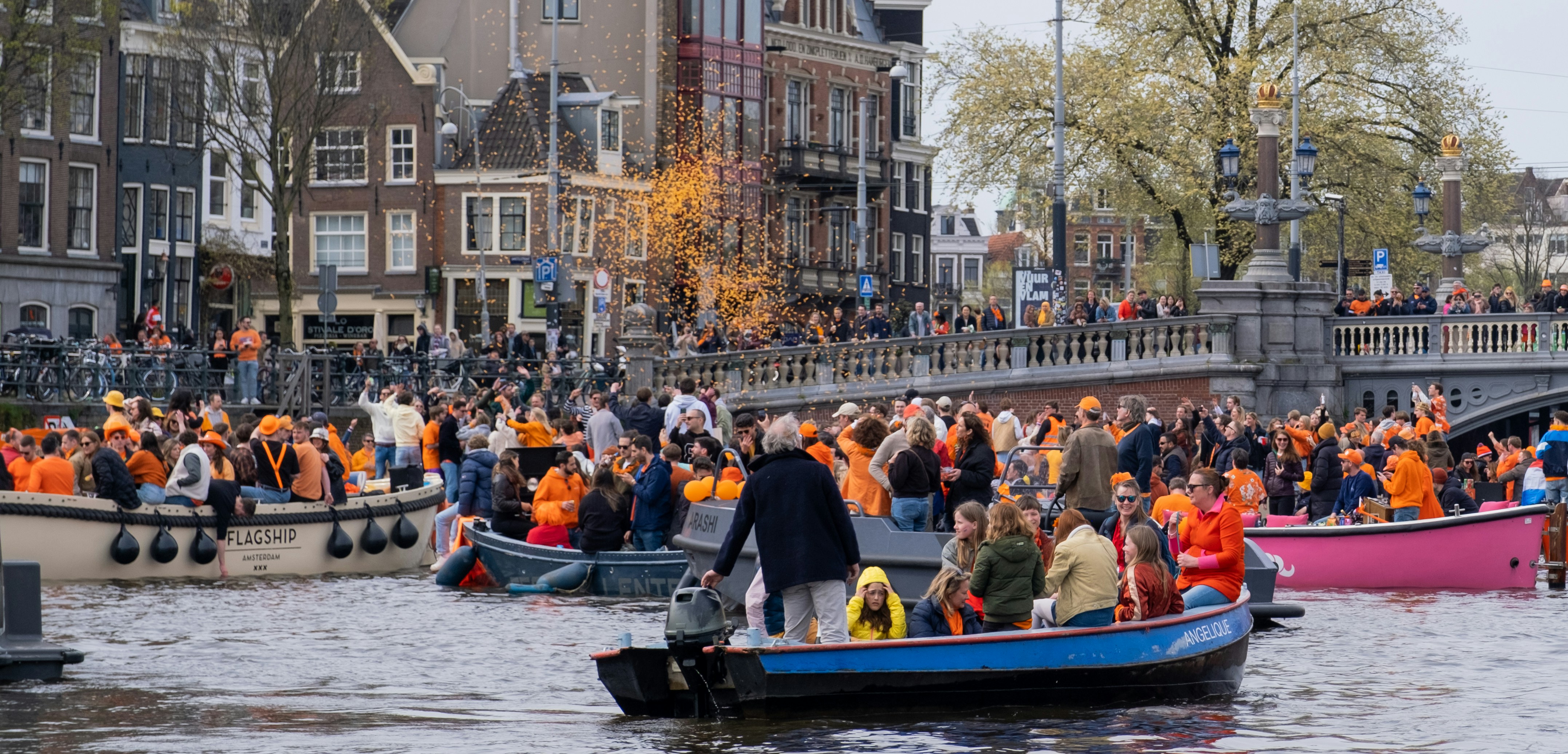 Boten vol mensen in oranje op de gracht tijdens Koningsdag